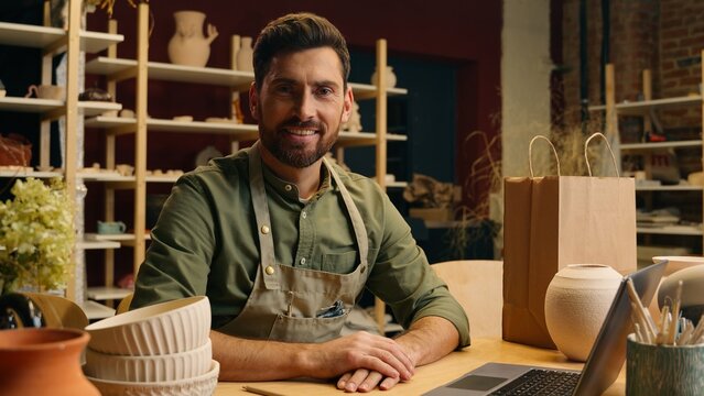 Careful Caucasian man guy businessman male small business owner potter salesman crock packing fragile clay bowl artwork pottery ceramic in shopping bag package typing laptop delivering indoor workshop - Powered by Adobe