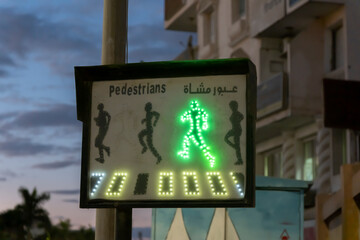 Busy street at twilight shows pedestrian crossing light signaling for safe passage in city area