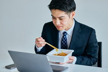 カップ焼きそばを食べながら仕事をする20代の若い男性