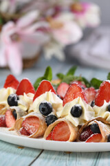 crepes filled with whipped cream, strawberries, and blueberries, dusted with powdered sugar.