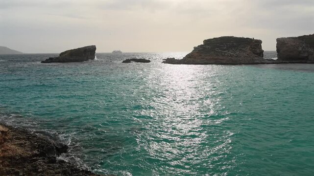 Malta Blue Lagoon landscape. Stunning view of the Blue Lagoon in Comino, Malta, showing the famous turquoise crystal clear waters and the rocky islet of Cominotto under a cloudy sky. 4k video