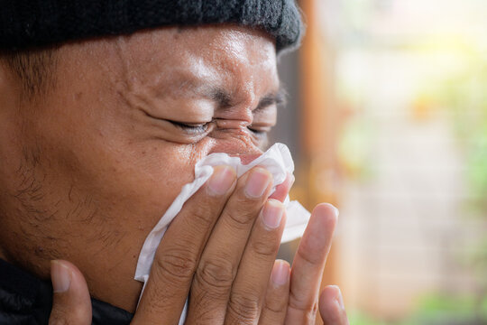 Asian man, cleaning his nose and house for respiratory influenza, allergies and sinus disease or infection. Viral disease and toilet paper to remove bacteria in the living room, fatigue and tissue for