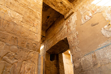 Historical site shows ancient carvings inside a stone structure with sunlight shining through openings, Luxor Temple