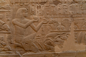 Ancient Egyptian carving showing a man offering items to deities in a temple setting, Luxor Temple