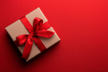 Top view of an elegant red gift box with red ribbon bow on red textured background, Christmas and Valentine's Day concept