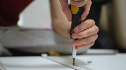 Positioning drawer rail on furniture base during dresser assembling. Installing metal slider on cabinet board while crafting woodworking project. Attaching guiding track on DIY drawer construction
