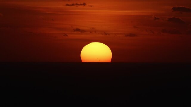 Dramatic sunset over the horizon of the Mediterranean Sea at Dingli Cliffs in Malta, with deep orange and red colors reflecting on the water under a dark cloudy sky. Sea sunset in Malta. 4k video