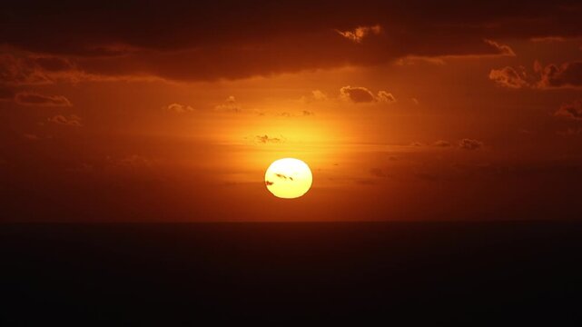 Dramatic sunset over the horizon of the Mediterranean Sea at Dingli Cliffs in Malta, with deep orange and red colors reflecting on the water under a dark cloudy sky. Sea sunset in Malta. 4k video