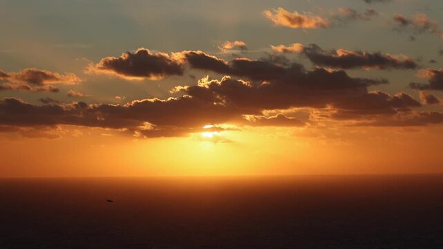 Dramatic sunset over the horizon of the Mediterranean Sea at Dingli Cliffs in Malta, with deep orange and red colors reflecting on the water under a dark cloudy sky. Sea sunset in Malta. 4k video