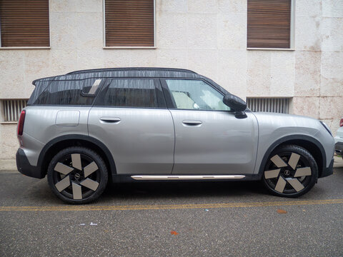 Silver Mini Countryman parked on a wet street in front of a building