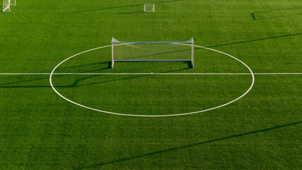 Symmetrical aerial shot of football goal aligned with center circle on artificial turf