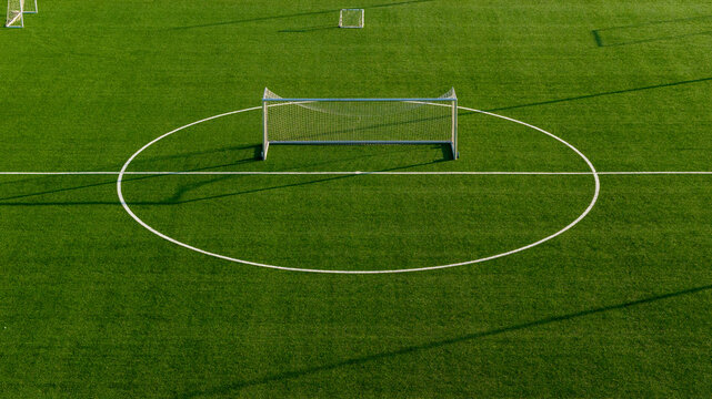 Symmetrical aerial shot of football goal aligned with center circle on artificial turf