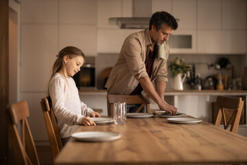 Father and daughter setting table for family lunch