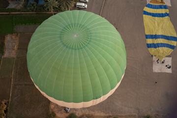 Hot air balloons are prepared for flight in a field during early morning in a rural area in Luxor
