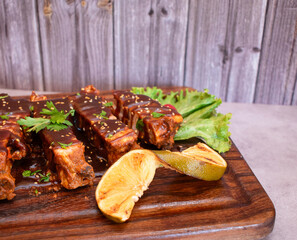 Esquina de una tabla de madera con costillas de cerdo bbq con naranja y lechuga