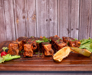 Imagen de una tabla de madera con carne asada de costila de cerdo