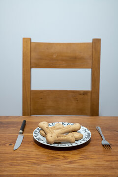 Dog's dinner table place. Bones on a plate with a knife and fork at a dining room table.