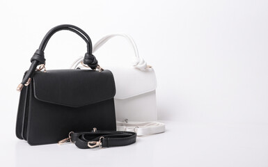Pair of elegant black and white leather handbags with knotted top handles. Stylish structured purses with matching detachable shoulder straps isolated on white background. Fashion product photo.