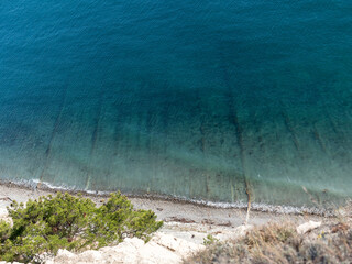 Panoramic view of the sea from a rocky hillside with pine trees under a clear blue summer sky