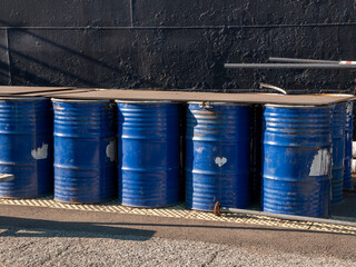 Stack of blue metal barrels outdoors. Industrial storage of steel drums in an organized pile