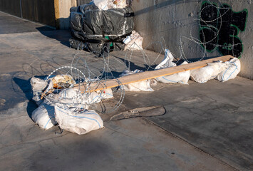 Barbed wire, sandbags and wooden boards blocking a passage and driveway. Temporary barricade and improvised barrier restricting access
