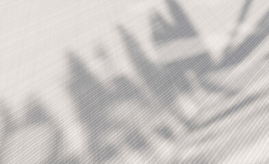 Plant leaf shadows overlaying a textured white fabric background with soft light