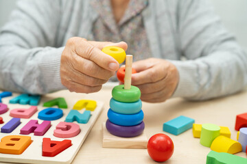 Asian elderly woman playing enhancing skill board game.