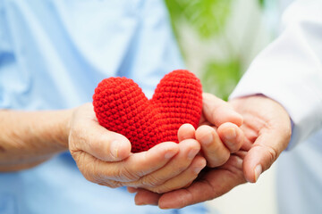 Asian elder senior woman patient holding red heart in hospital.