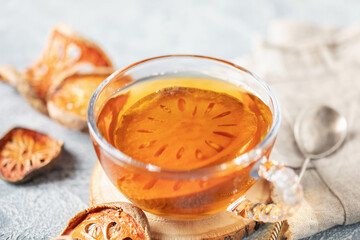 Thai healing matoom tea made of dried bael fruit slices, also known as wood apple, in transparent glass cup on the table