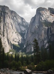 Majestic granite cliffs of a deep mountain valley, with a winding river and lush green forest under a cloudy sky.