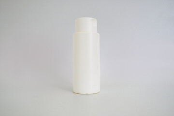 A white cosmetic bottle mockup for shampoo, lotion, or toner. A plastic bottle with a dispenser cap and no label, isolated on a gray background