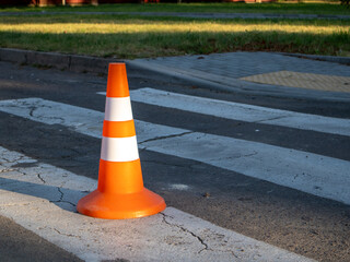 Traffic cone stands on crosswalk marking in the street