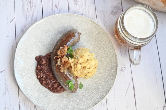 Traditional Czech food background featuring beer and classic slaughterhouse specialties such as blood sausages (jitrnice) and pork p&acirc;t&eacute; (prejt) arranged on a rustic wooden cutting board.
