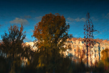 Distorted image of apartment house and trees on river surface