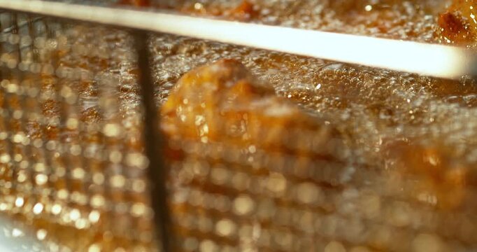 Crispy Chicken Karaage coming out from the hot Fryer oil in Macro Super Slow Motion