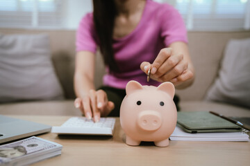 A close-up image shows a woman planning a trip and her finances at home, holding her passport and planner. Cash, a calculator, a piggy bank, and a laptop are on a table, illustrating budgeting and tra
