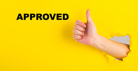 Hand giving thumbs up with approved text