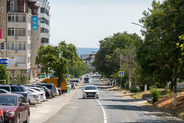 August 24, 2025: Town road in Myskhako, Russia, with cars and residential houses, mountains and the sea in the background, showing everyday life and coastal urban landscape