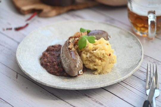 Traditional Czech food background featuring beer and classic slaughterhouse specialties such as blood sausages (jitrnice) and pork p&acirc;t&eacute; (prejt) arranged on a rustic wooden cutting board.