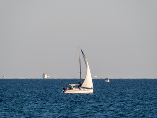 Obraz premium August 22 2025 Sailing yacht Uspekh with white sail on the Black Sea near Novorossiysk Russia. Recreational yacht moving along the coastline.