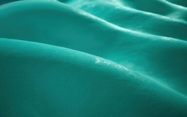 Sparkling turquoise fabric waves gently undulating with soft folds and subtle sheen