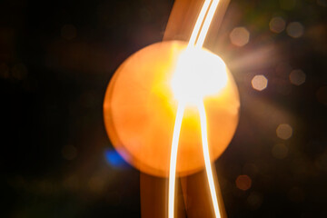 Abstract image featuring flowing light trails, creating curved lines with a warm, glowing tone. The light paints an organic, dynamic texture against a dark background