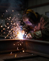 Welder with Sparks Flying in Dark Factory - Industrial Manufacturing