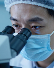 Researcher Looking Through Microscope in Blue Light - Scientific Discovery
