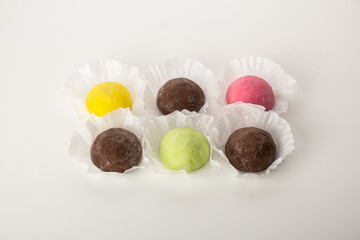 Colorful assortment of round confectionery treats displayed on white paper liners, featuring vibrant hues of yellow, pink, green, and brown, ideal for dessert lovers and culinary enthusiasts