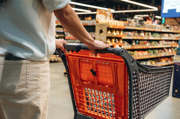 Individual pushing shopping cart through grocery store aisle filled with various products, showcasing the modern shopping experience and consumer culture © standret