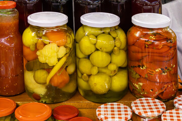 Organic pickled vegetables inside glass jars in home pantry interior