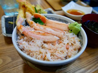 HAKODATE, JAPAN – JULY 23, 2025: A bowl of fresh Kani Don (Crab on Rice) featuring premium local crab meat with Tempura in the background, served at a seafood market in Hakodate, Hokkaido. © Chonlatit