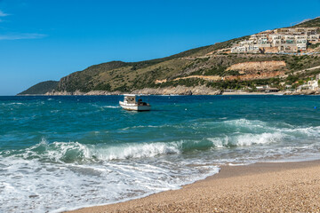 Obraz premium Brandung am Strand mit Boot in der Ferne, Jala, Qark Vlora, Albanien