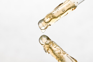 Two pipettes with yellow serum, aromatherapy gel on a light background.